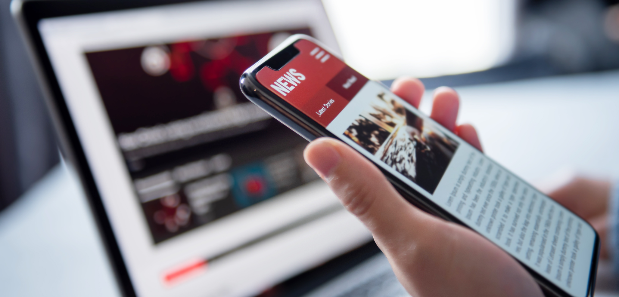 Layer 86 Hand holding phone with news app open